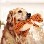 Golden retriever jouant joyeusement avec un jouet dinosaure orange dans un intérieur chaleureux.