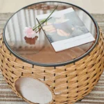 Table ronde en rattan avec verre, fleur rose et espace pour animal de compagnie.