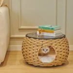 Table en osier avec coin cosy pour chat et livres décoratifs dans un salon élégant.