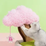 Un chat curieux joue avec un arbre en fleurs rose, idéal pour animaux de compagnie.