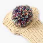 Bonnet crème avec pompon coloré, parfait pour rester au chaud et stylé cet hiver.