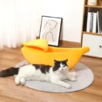 Un chat blanc détendu dans un lit en forme de banane dans un intérieur chaleureux.