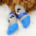 Chaussettes grises pour chien avec visages de ours et semelles bleues antidérapantes.