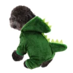 Un adorable chien en costume de dinosaure vert, curieux et joyeux.