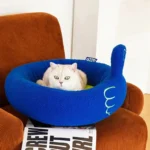 Un chat blanc détendu dans un lit bleu sur un fauteuil orange confortable.