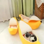 Lits de chat en forme de banane jaunes, avec un chat noir et blanc relaxé.