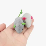 Deux petites souris en peluche mignonnes tenues dans une main.