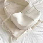 Sac à main blanc moderne avec housse douce sur fond neutre élégant.