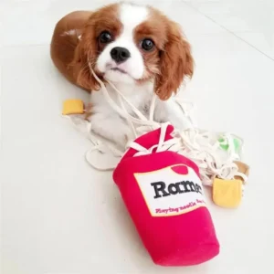 Cavalier King Charles Spaniel joue avec un jouet en forme de boîte à ramen.