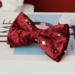 Noeud papillon rouge en velours avec étoiles dorées, idéal pour les occasions festives.