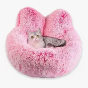 Un chat adorable se repose dans un lit rose doux en forme doreilles de chat.