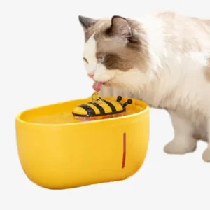 Un chat curieux boit dans un bol deau jaune avec un jouet abeille flottant.