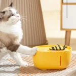 Un chat crème et brun joue avec un jouet jaune, capturant un moment de curiosité.