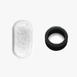 Objet oval transparent et bague noire en matériau mat sur fond clair.