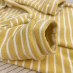 Tissu doux jaune et blanc, idéal pour des vêtements confortables et des décorations accueillantes.