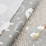 Tissu gris ludique avec lapins, nuages et cœurs, idéal pour décoration enfantine.