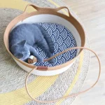 un chat bleu allonge dans un panier chat en rotin avec un coussin motif vagues