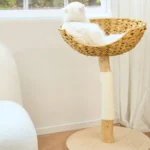 Un chat blanc allongé dans un arbre à chat avec niche en osier
