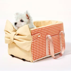 Un petit chien dans un panier pour animal sur l'accoudoir de voiture avec motif oiseaux orange.