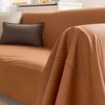 Gros plan sur l'accoudoir de la housse de canapé orange extensible anti-griffure